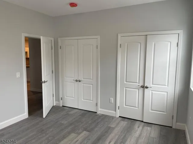 an empty room with wooden floor & closet area