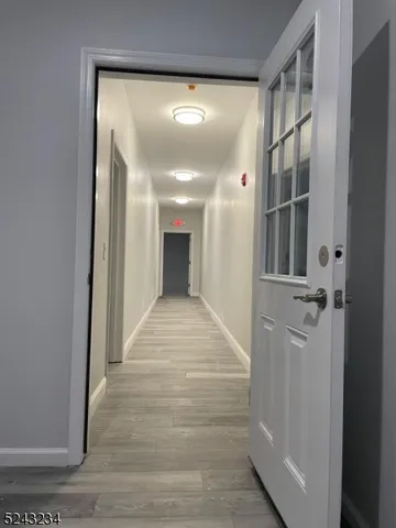 a view of a hallway with wooden floor and a bathroom