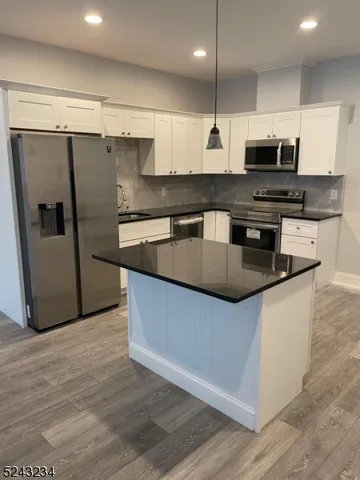 a kitchen with stainless steel appliances granite countertop a refrigerator a stove a sink and a microwave