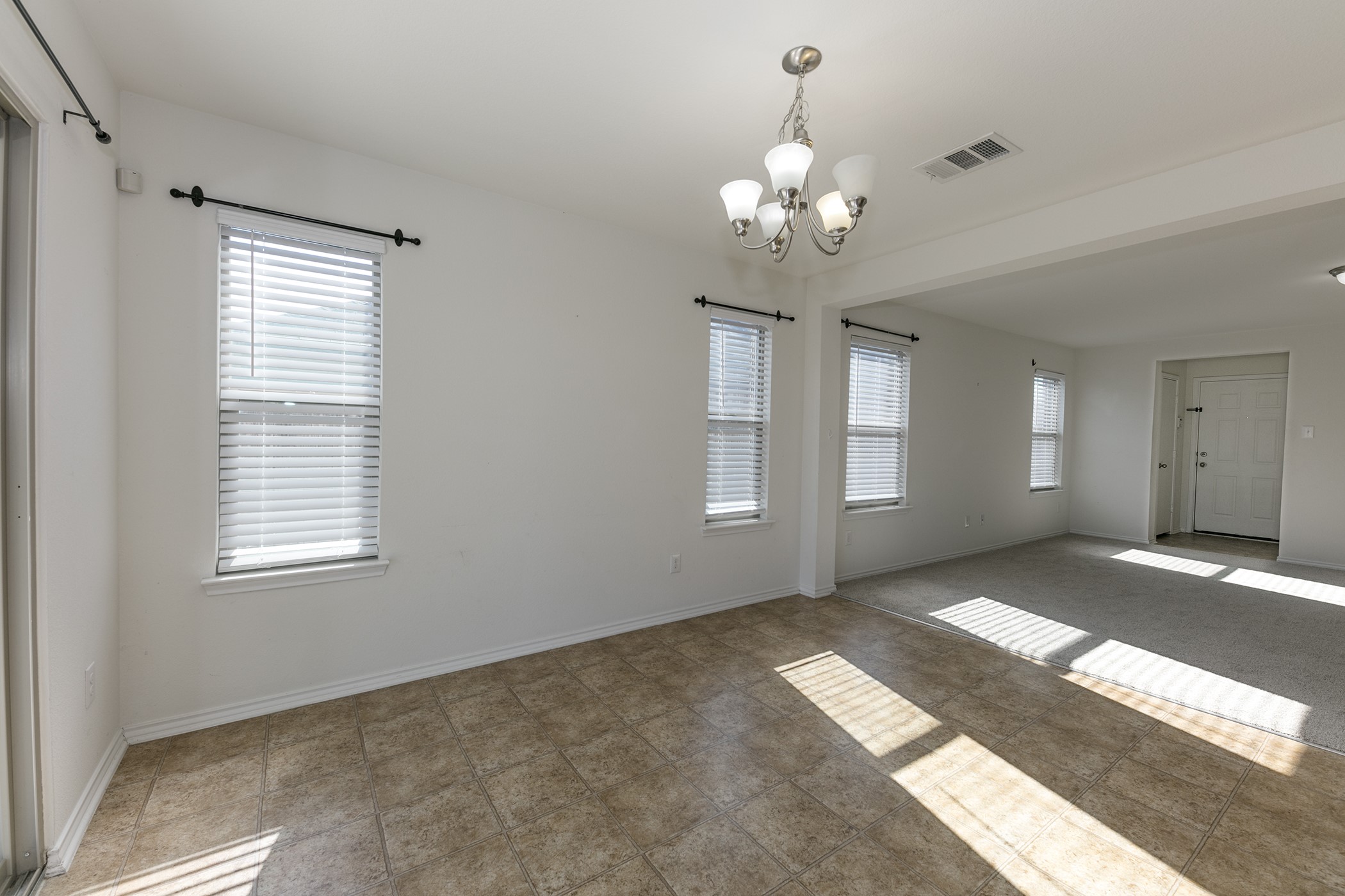 1141 Renaissance Trail Round Rock, TX 78665 - Photo 5 of 23 Sun-drenched living area featuring tile flooring, multiple windows, and a classic chandelier.