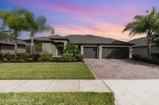 front view of a house with a yard and palm trees