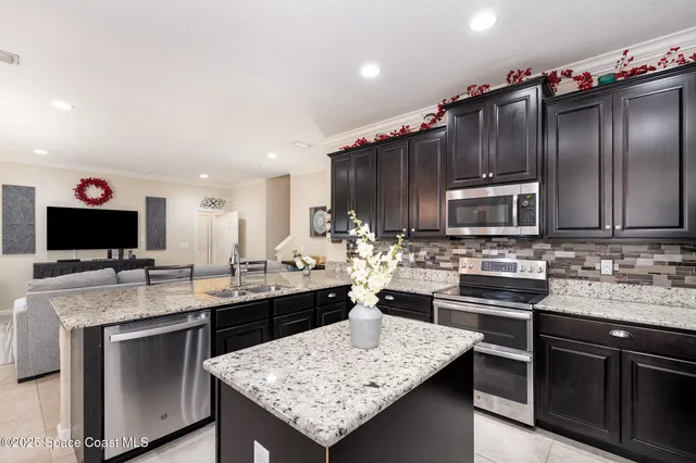 a kitchen with stainless steel appliances kitchen island granite countertop a sink stove and refrigerator
