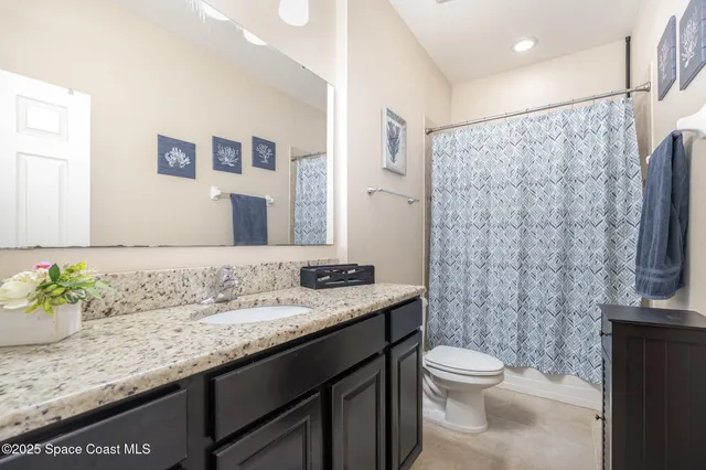 a bathroom with a granite countertop sink a toilet and a mirror