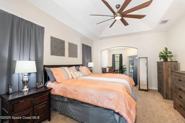 a spacious bedroom with a bed a dresser and a chandelier