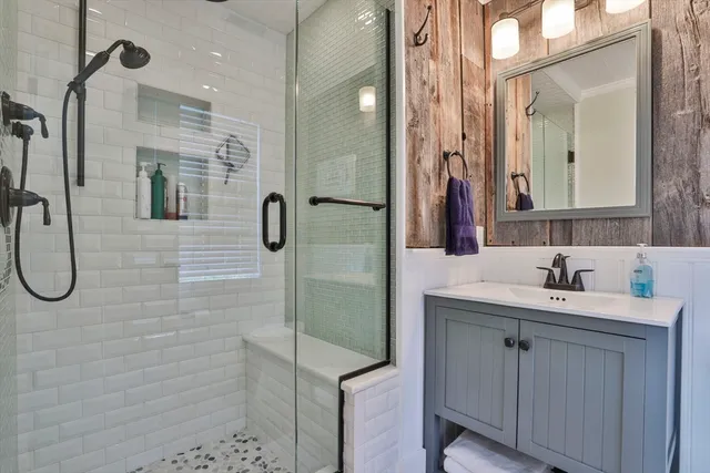 a bathroom with a sink a toilet a mirror and shower