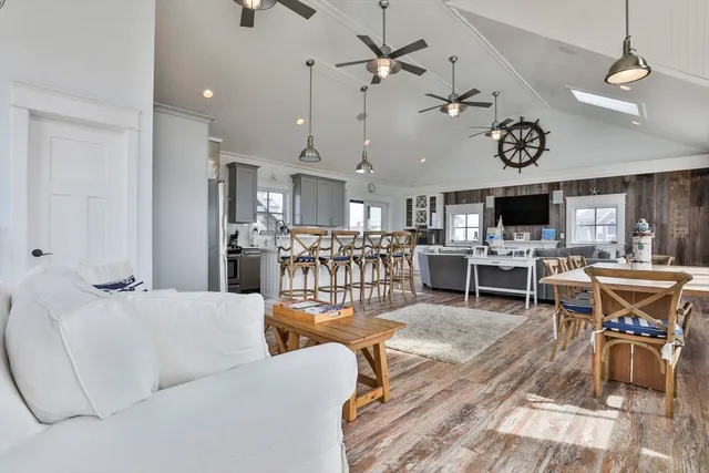 a living room with lots of furniture kitchen view and a chandelier