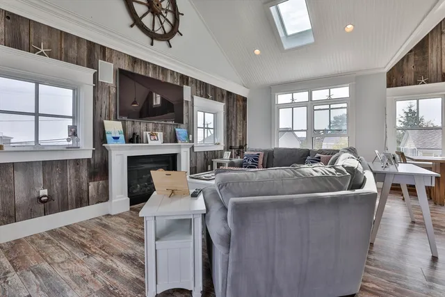 a living room with stainless steel appliances granite countertop furniture a fireplace a flat screen tv and a window