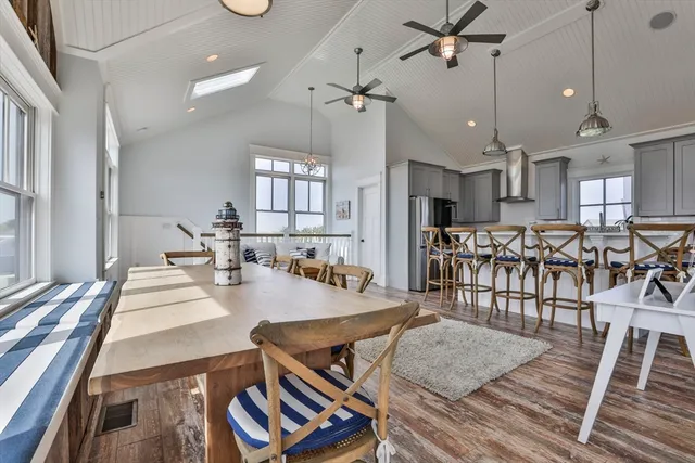 a kitchen with stainless steel appliances granite countertop a stove a sink a dining table and chairs with wooden floor