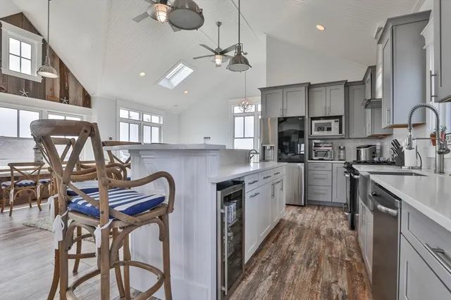 a kitchen with stainless steel appliances kitchen island granite countertop a table chairs refrigerator and sink