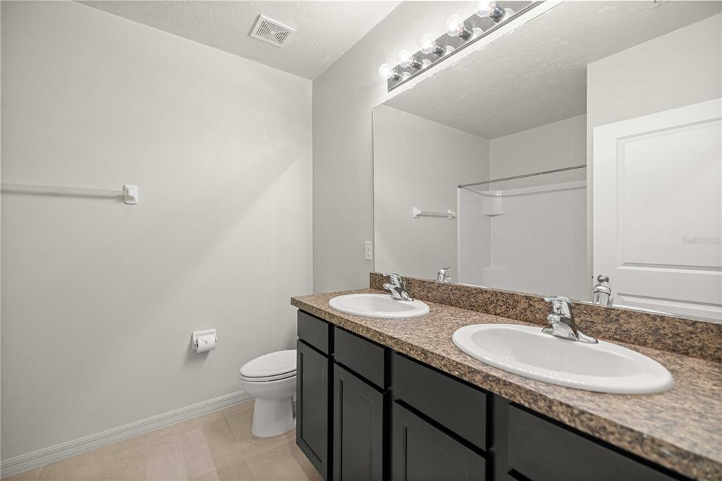 3902 Southeast 99th Street Belleview, FL 34420 - Photo 22 of 28 a bathroom with a granite countertop sink a toilet and a mirror