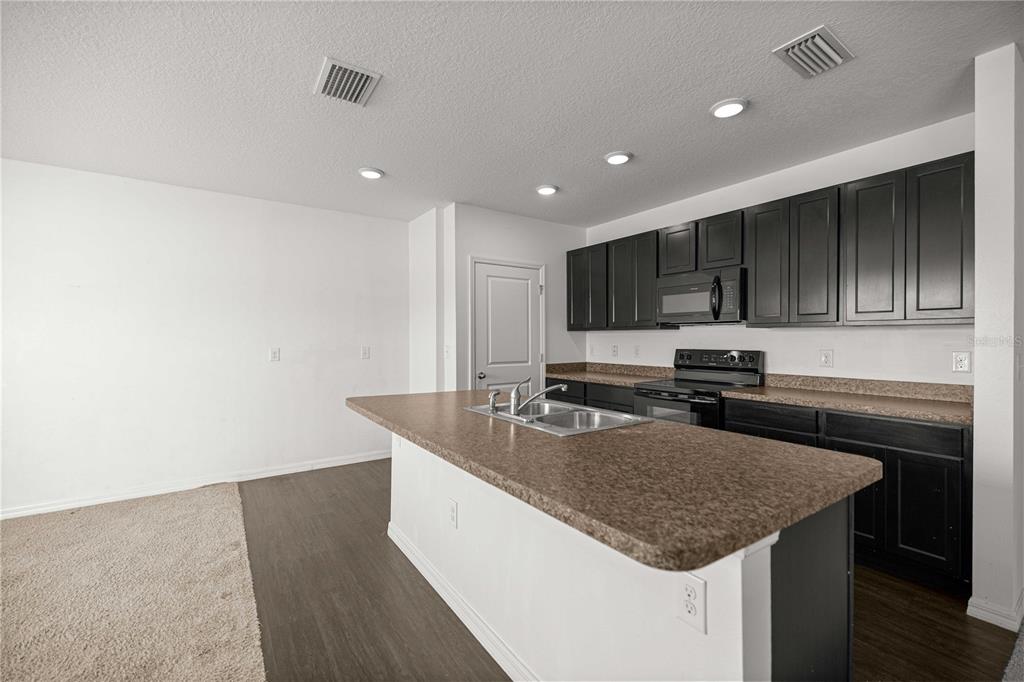 3902 Southeast 99th Street Belleview, FL 34420 - Photo 10 of 28 a kitchen with granite countertop stainless steel appliances a sink stove refrigerator and cabinets