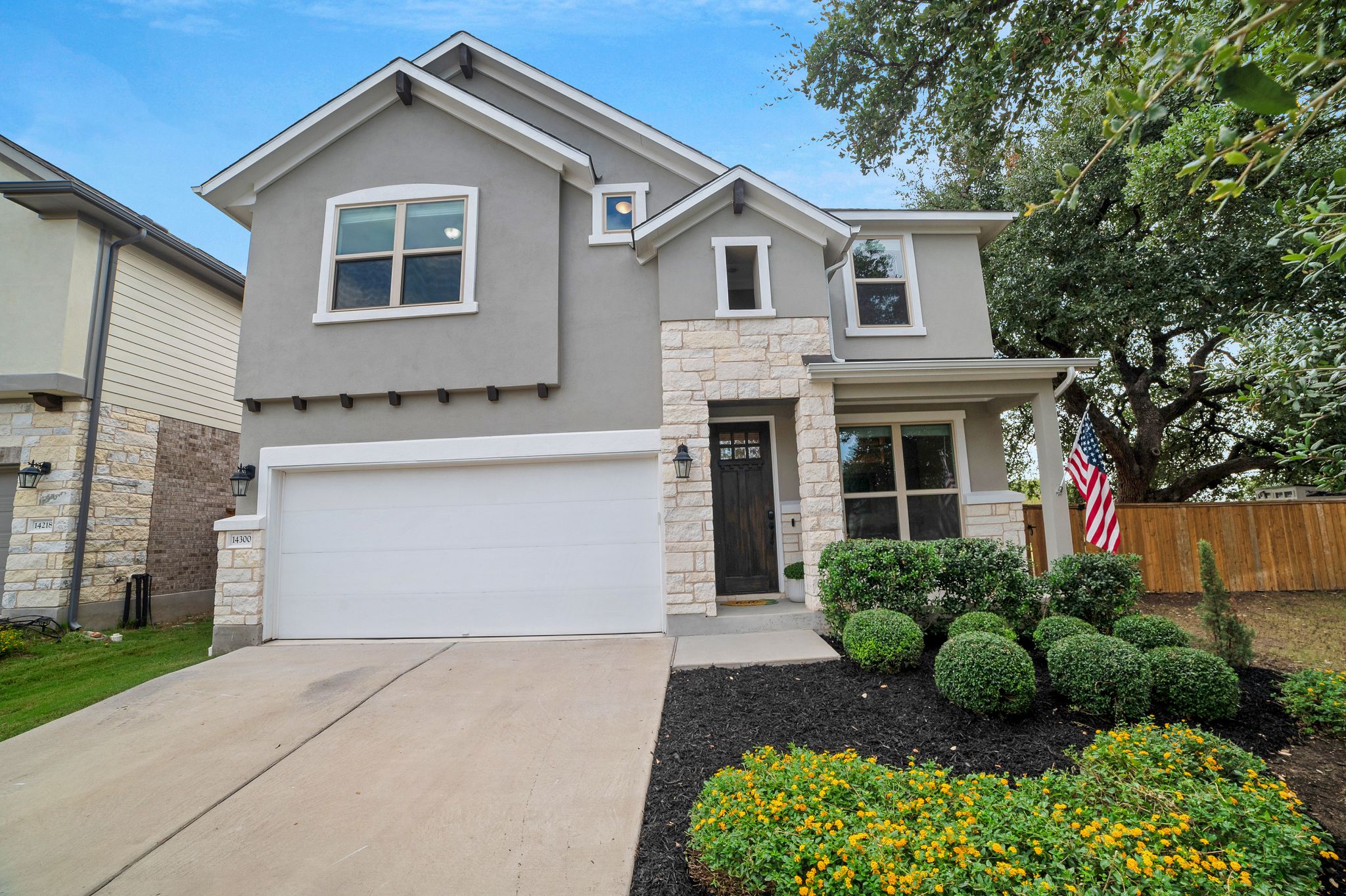 The property features a stucco and stone facade, a two-car garage, and a well-maintained front yard with mature landscaping
