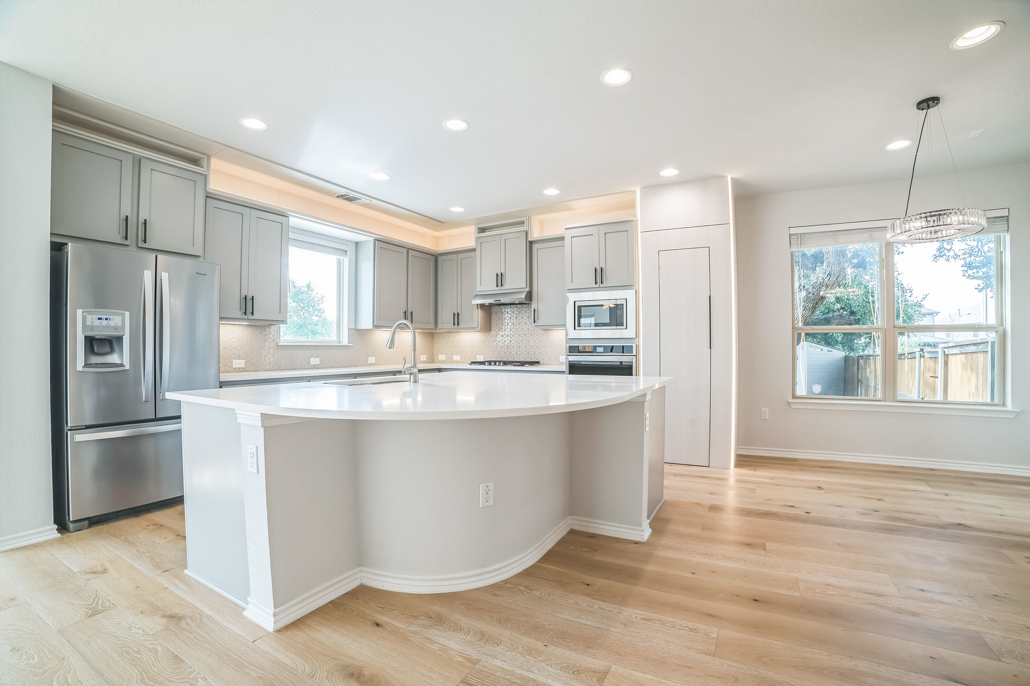 14300 McCoy Loop, Unit 21 Austin, TX 78717 - Photo 14 of 40 This kitchen features stainless steel appliances, light gray cabinetry, a white countertop island, and wood flooring