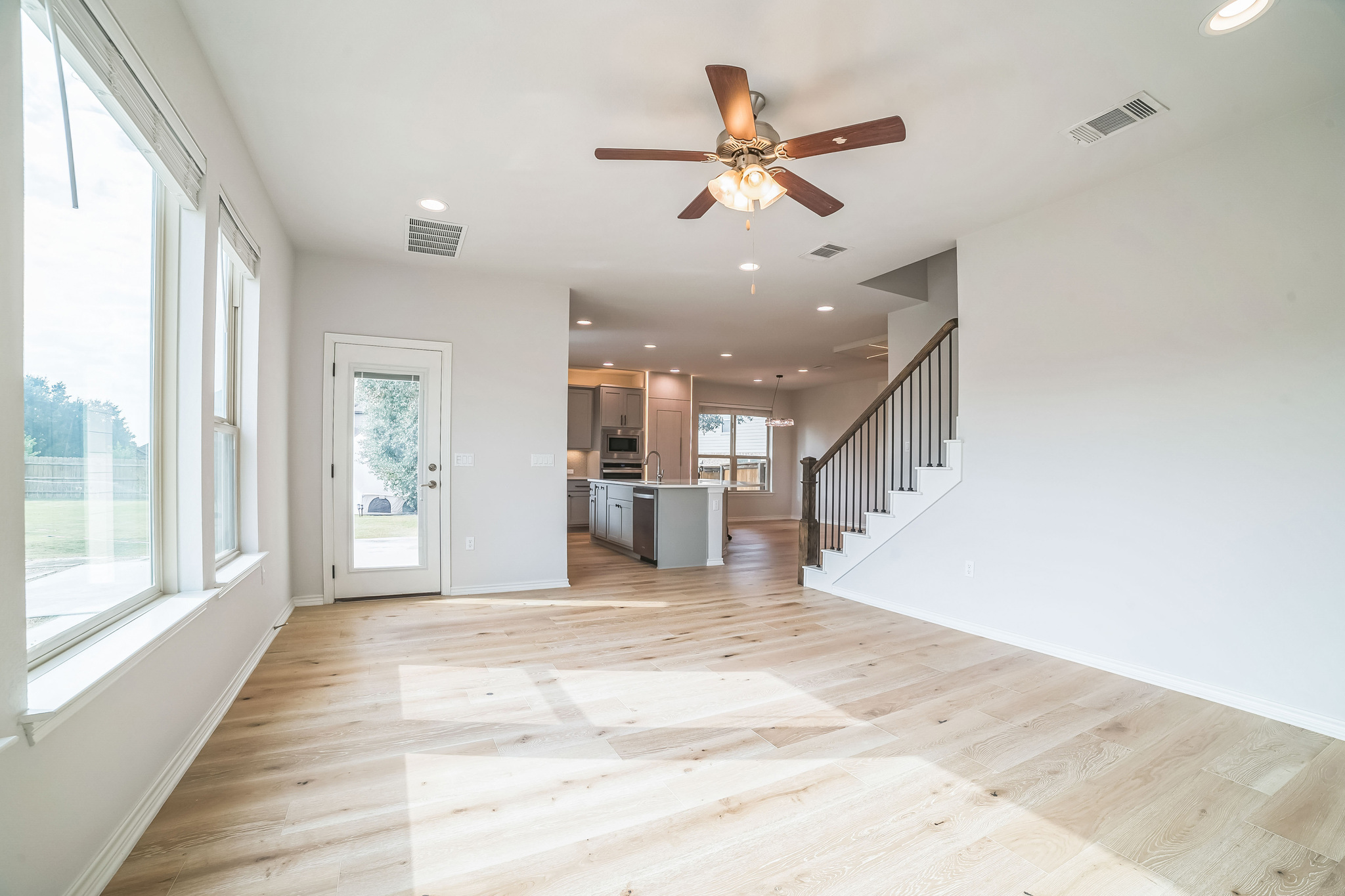 14300 McCoy Loop, Unit 21 Austin, TX 78717 - Photo 15 of 40 Bright living area with light-toned flooring, expansive windows providing outdoor views, a ceiling fan with integrated lighting, and a view of the kitchen area