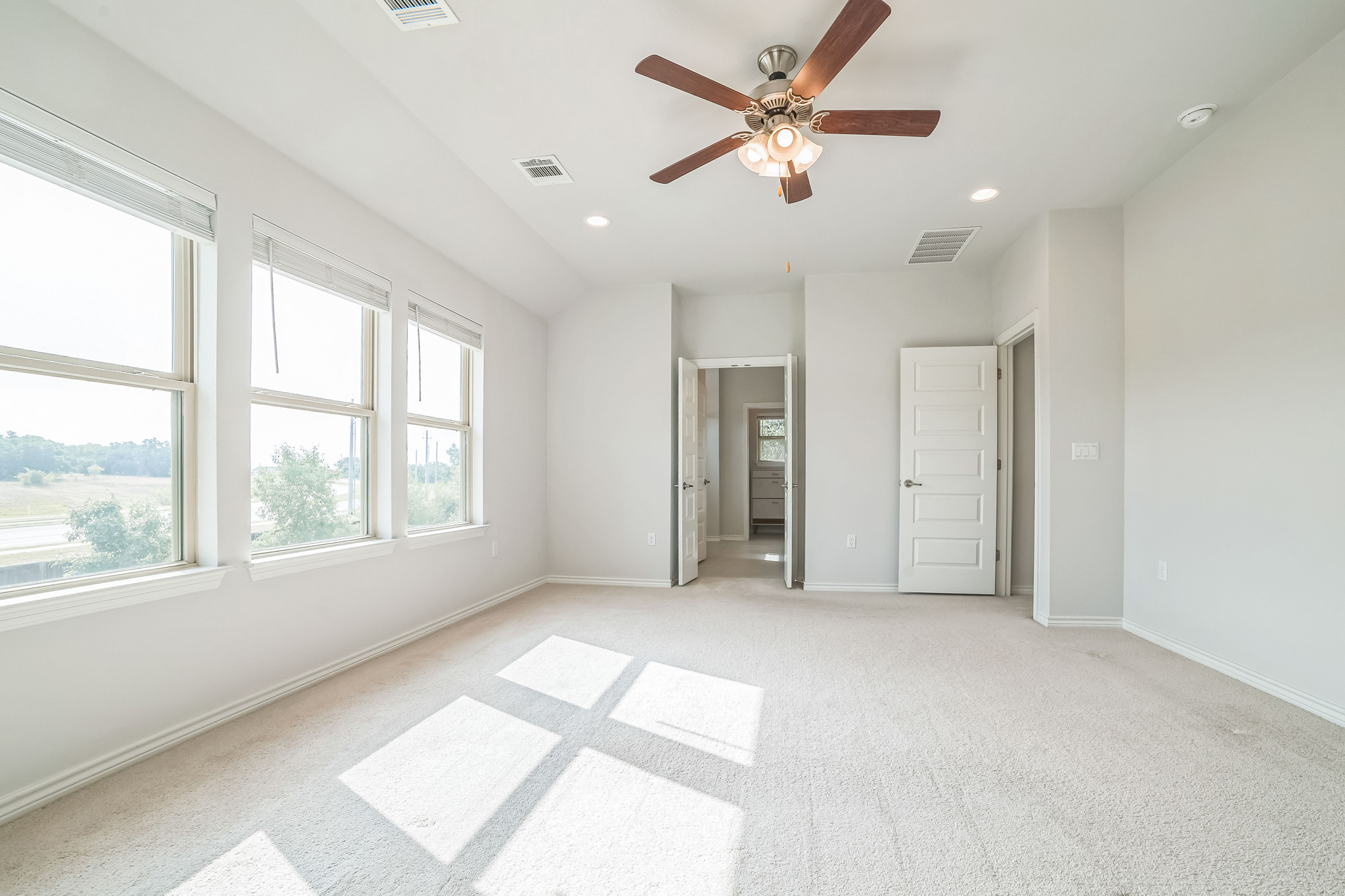 14300 McCoy Loop, Unit 21 Austin, TX 78717 - Photo 20 of 40 Spacious room featuring light-colored carpeting, three large windows providing natural light, and a ceiling fan with integrated lighting
