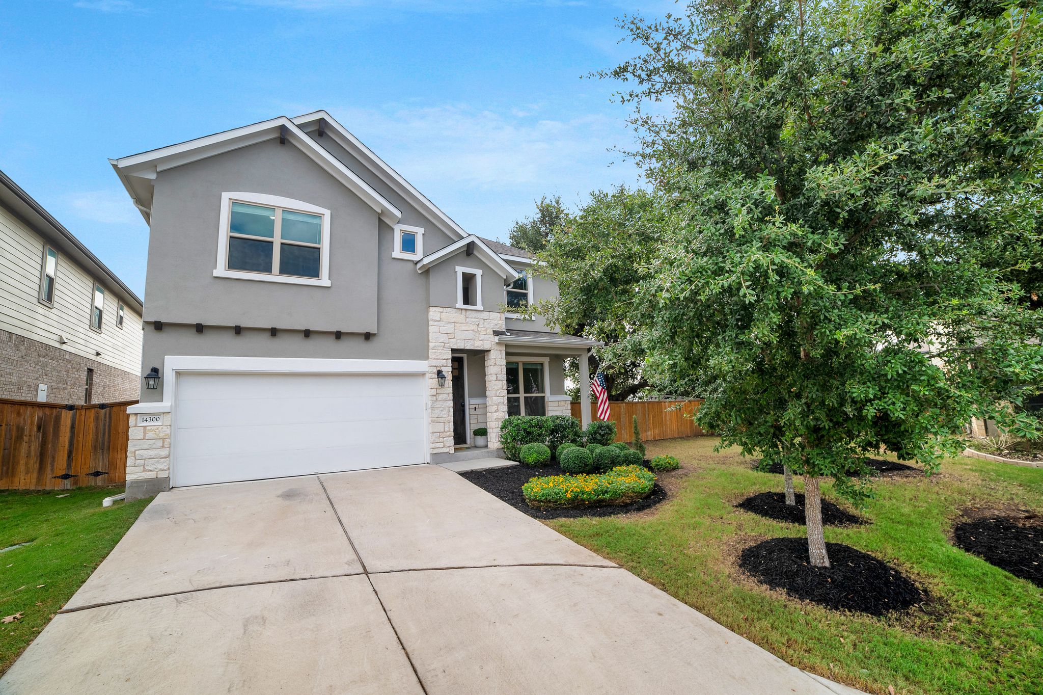 14300 McCoy Loop, Unit 21 Austin, TX 78717 - Photo 2 of 40 This property features a gray exterior with stone accents, a white garage door, and a concrete driveway