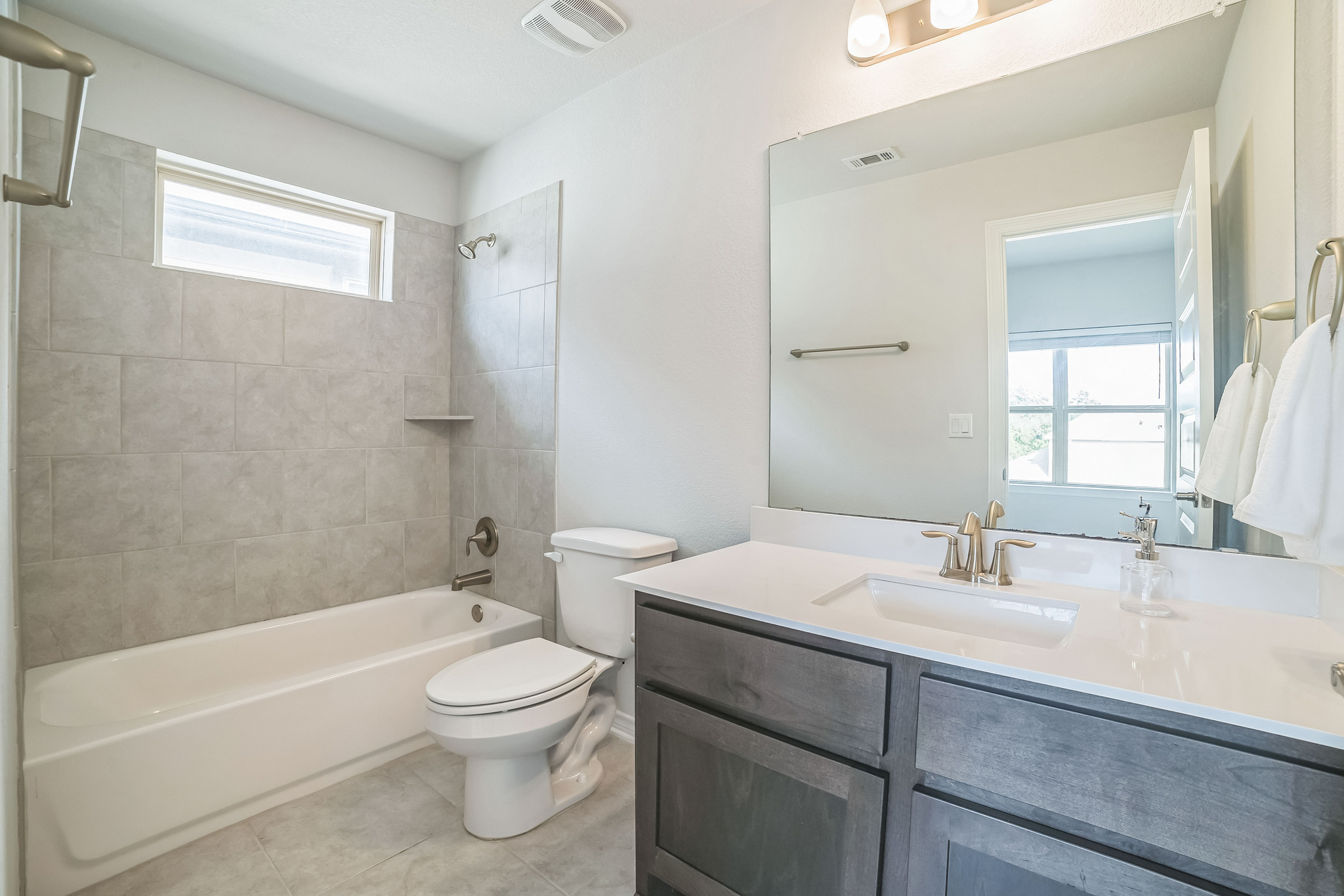 14300 McCoy Loop, Unit 21 Austin, TX 78717 - Photo 31 of 40 Bathroom featuring a vanity with a white countertop and a rectangular sink, a large mirror, a toilet, and a bathtub with tiled walls