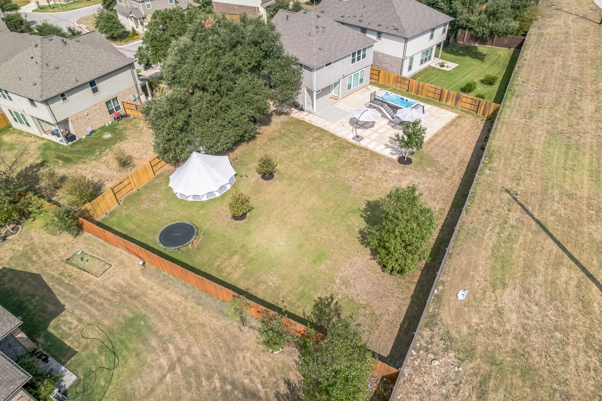 14300 McCoy Loop, Unit 21 Austin, TX 78717 - Photo 40 of 40 Expansive backyard featuring a large grass area, mature trees, and a wooden fence