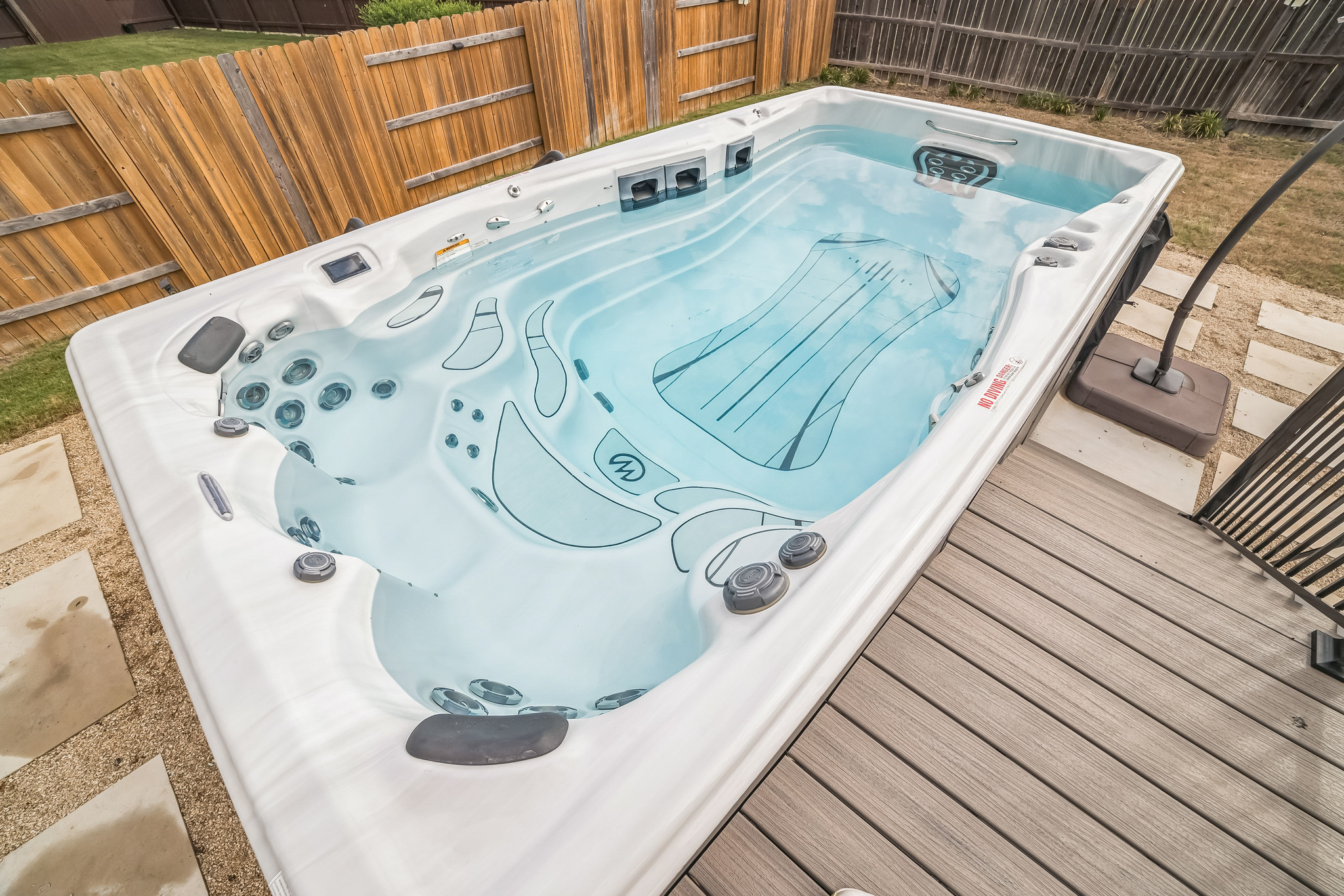 14300 McCoy Loop, Unit 21 Austin, TX 78717 - Photo 4 of 40 The property features a swim spa with clear water, surrounded by a wooden privacy fence and a composite deck