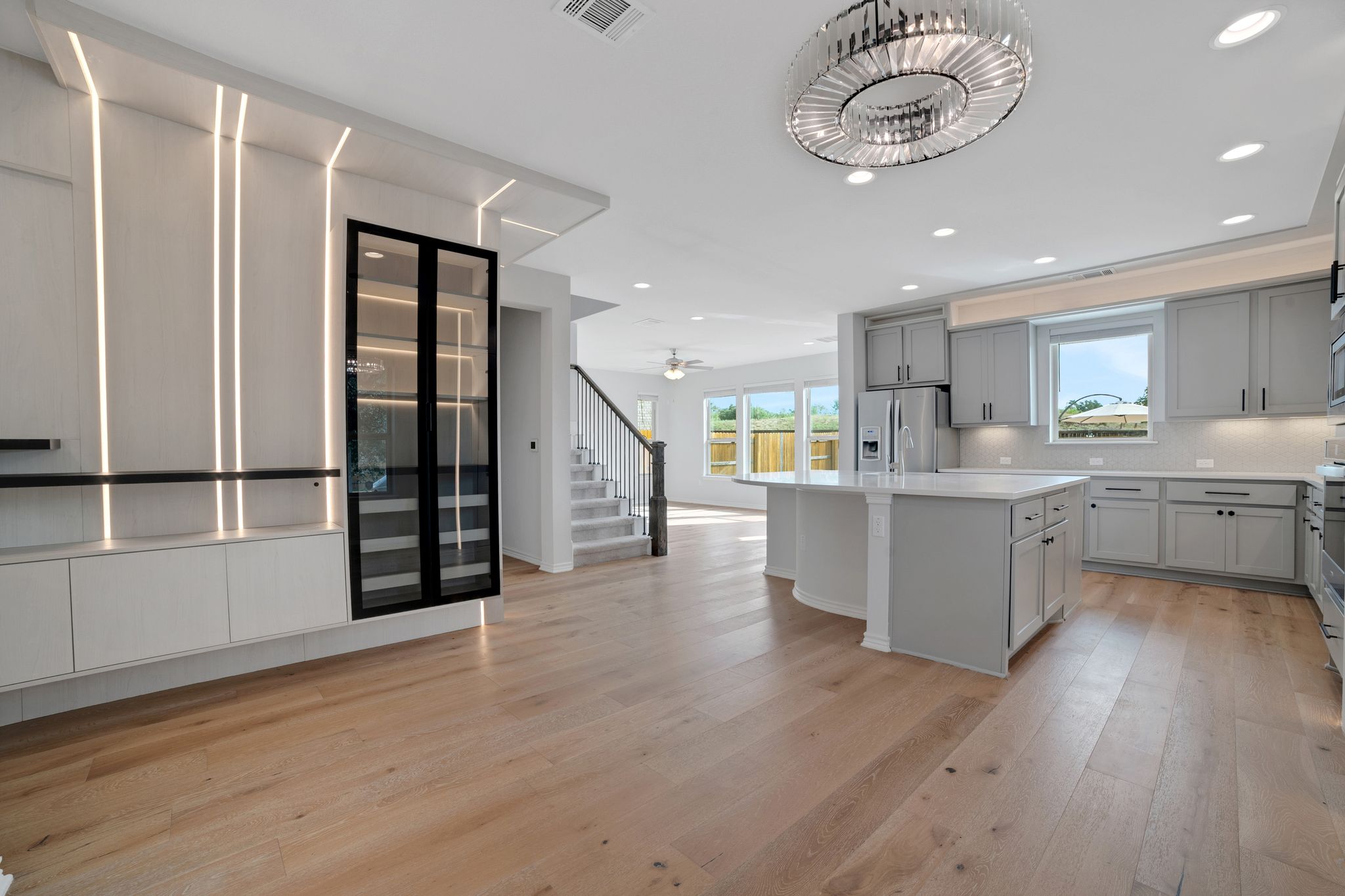 14300 McCoy Loop, Unit 21 Austin, TX 78717 - Photo 7 of 40 Open-concept living space featuring light wood flooring, a modern chandelier, and a kitchen with an island, grey cabinetry, and stainless steel appliances