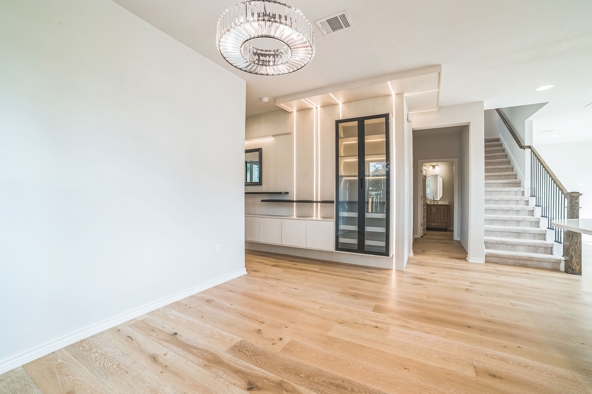 14300 McCoy Loop, Unit 21 Austin, TX 78717 - Photo 9 of 40 Spacious interior with light wood flooring, a modern overhead light fixture, and a built-in display cabinet with glass doors