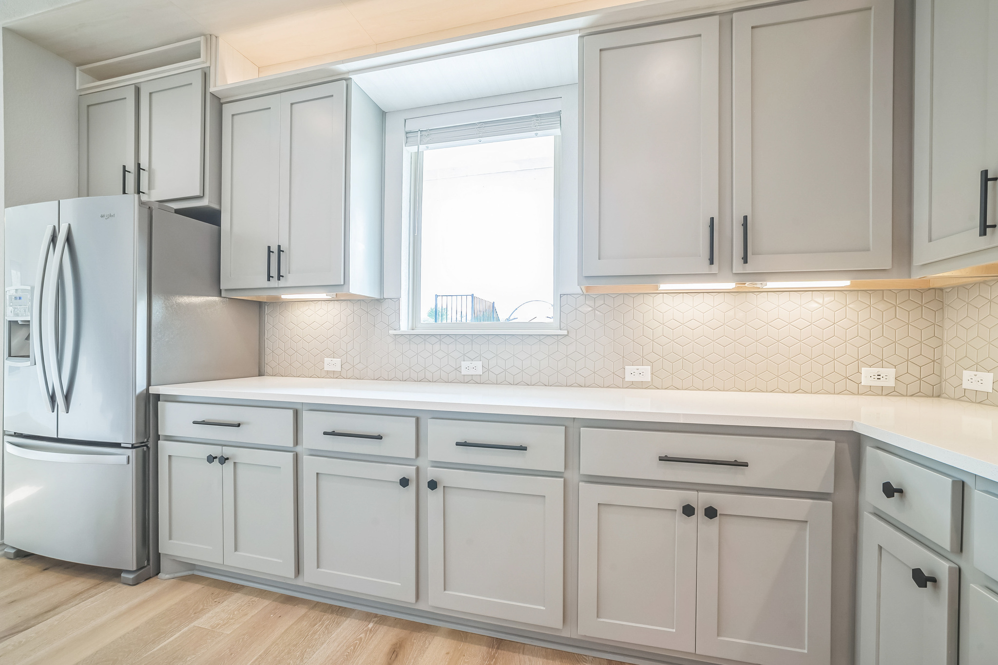 14300 McCoy Loop, Unit 21 Austin, TX 78717 - Photo 10 of 40 The kitchen features light-colored cabinetry with dark hardware, white countertops, and a patterned tile backsplash