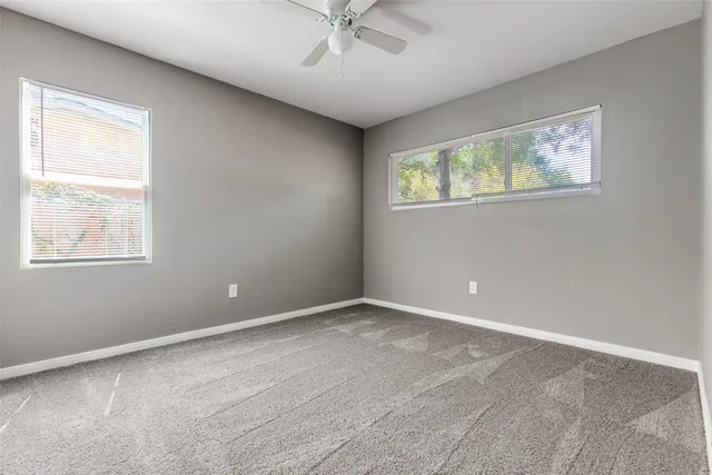 an empty room with windows and ceiling fan