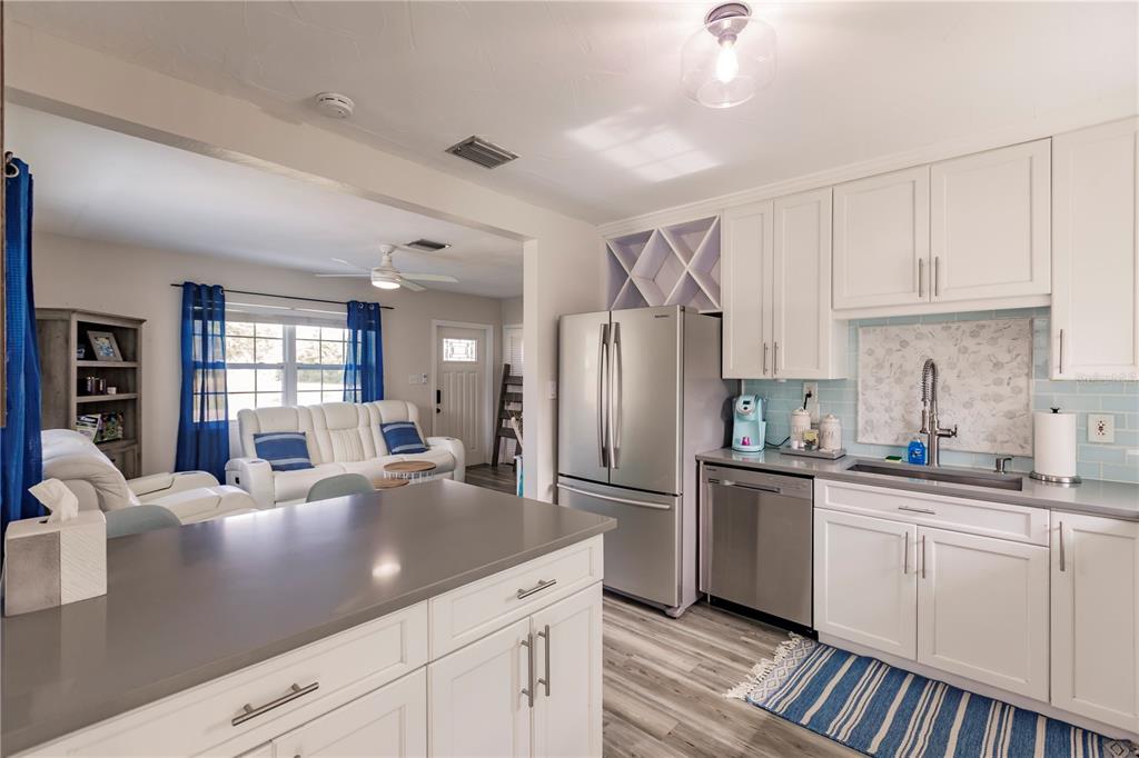 688 Constance Road Venice, FL 34293 - Photo 4 of 11 a kitchen with stainless steel appliances granite countertop a sink dishwasher a refrigerator and white cabinets with wooden floor