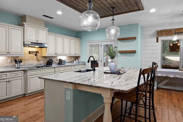 a kitchen with stainless steel appliances granite countertop a dining table chairs sink and cabinets