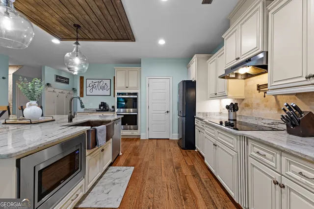 a kitchen with granite countertop a sink stainless steel appliances and cabinets