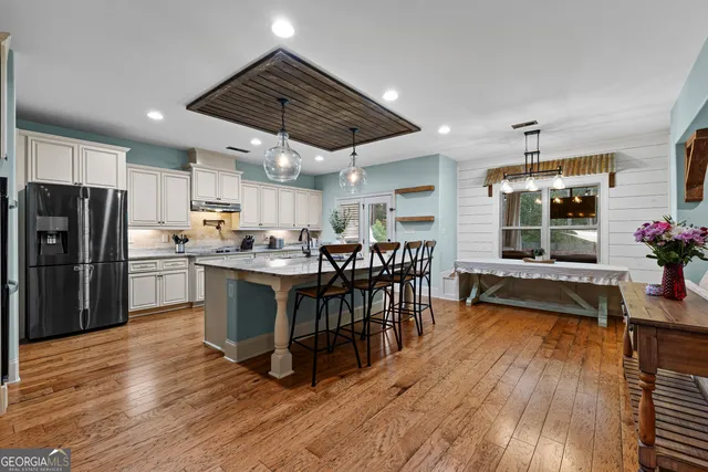 a kitchen with stainless steel appliances a dining table chairs stove and refrigerator