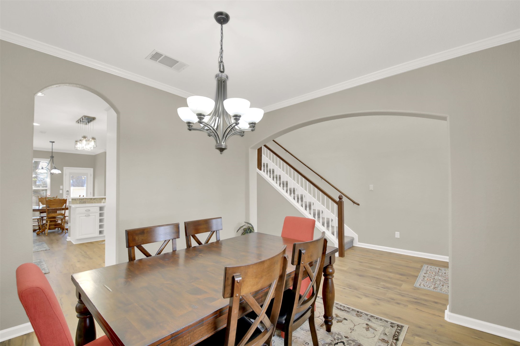 1210 Mathias Street Cedar Park, TX 78613 - Photo 3 of 31 Dining area featuring arched walkways, hanging lights, light wood-style floors, and ornamental molding