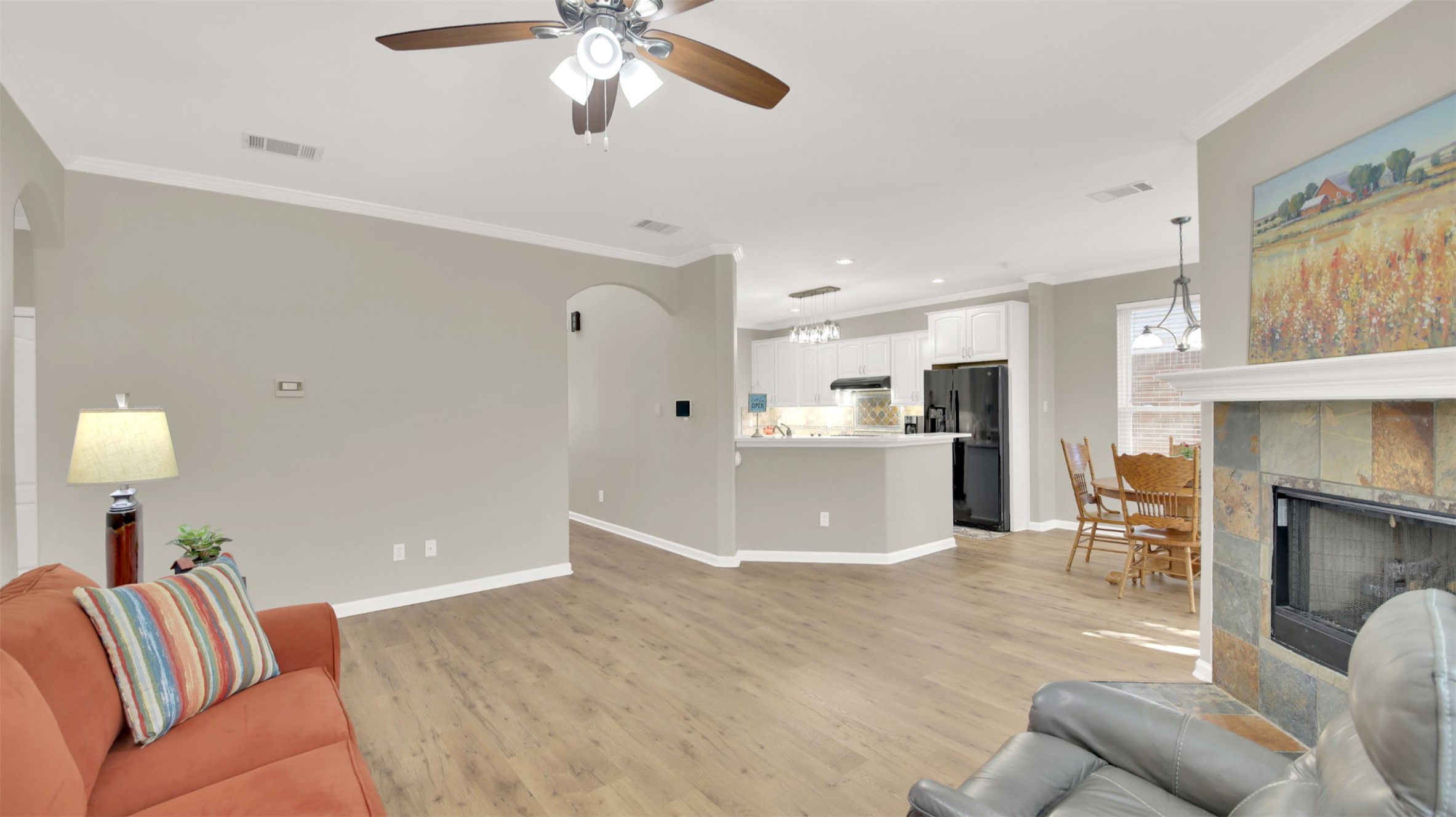1210 Mathias Street Cedar Park, TX 78613 - Photo 6 of 31 Living area featuring light wood-style floors, a ceiling fan, ornamental molding, arched walkways, and a fireplace