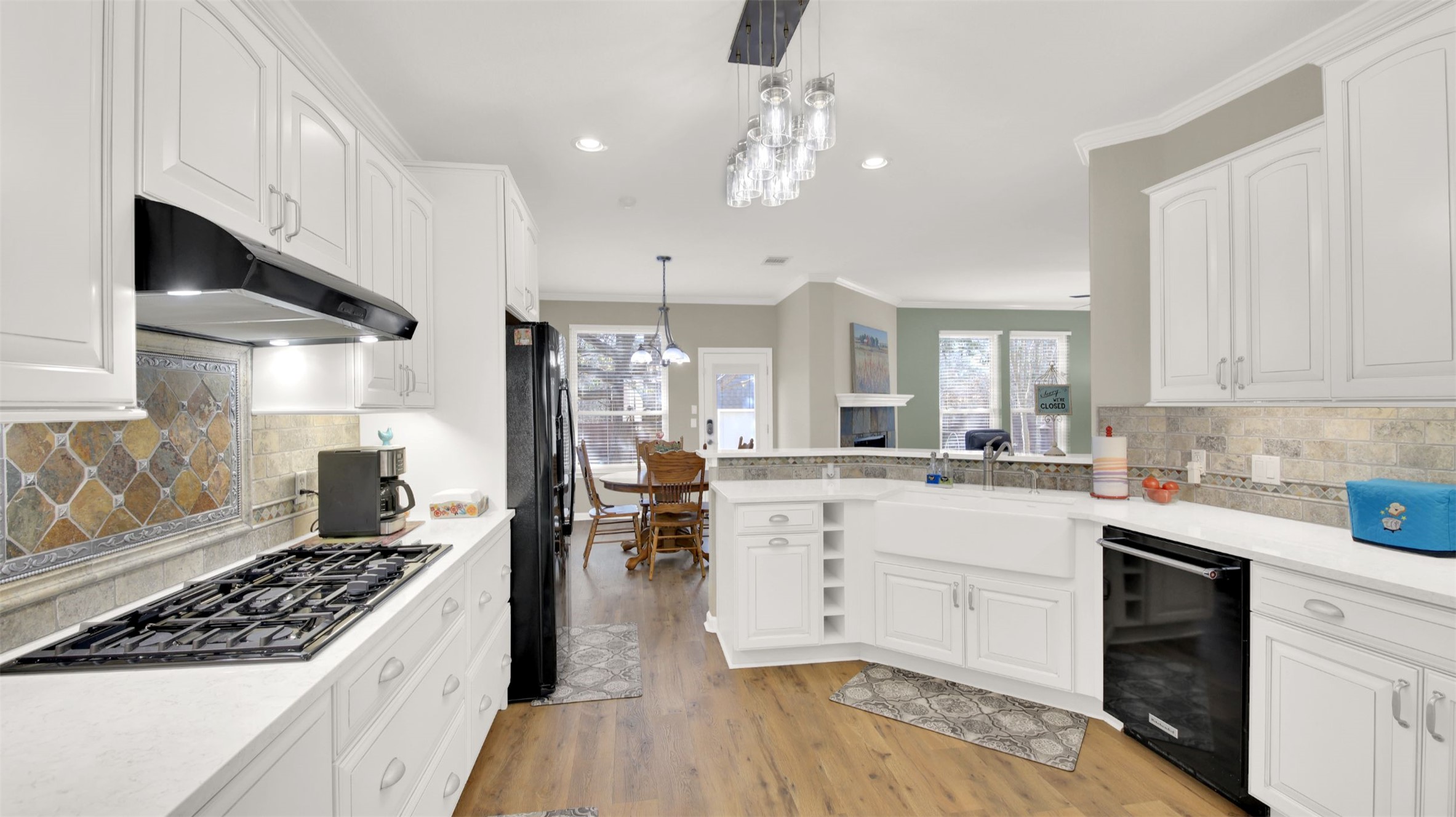 1210 Mathias Street Cedar Park, TX 78613 - Photo 8 of 31 Kitchen featuring white cabinetry, black fridge with ice dispenser, tasteful backsplash, ornamental molding, and light stone countertops