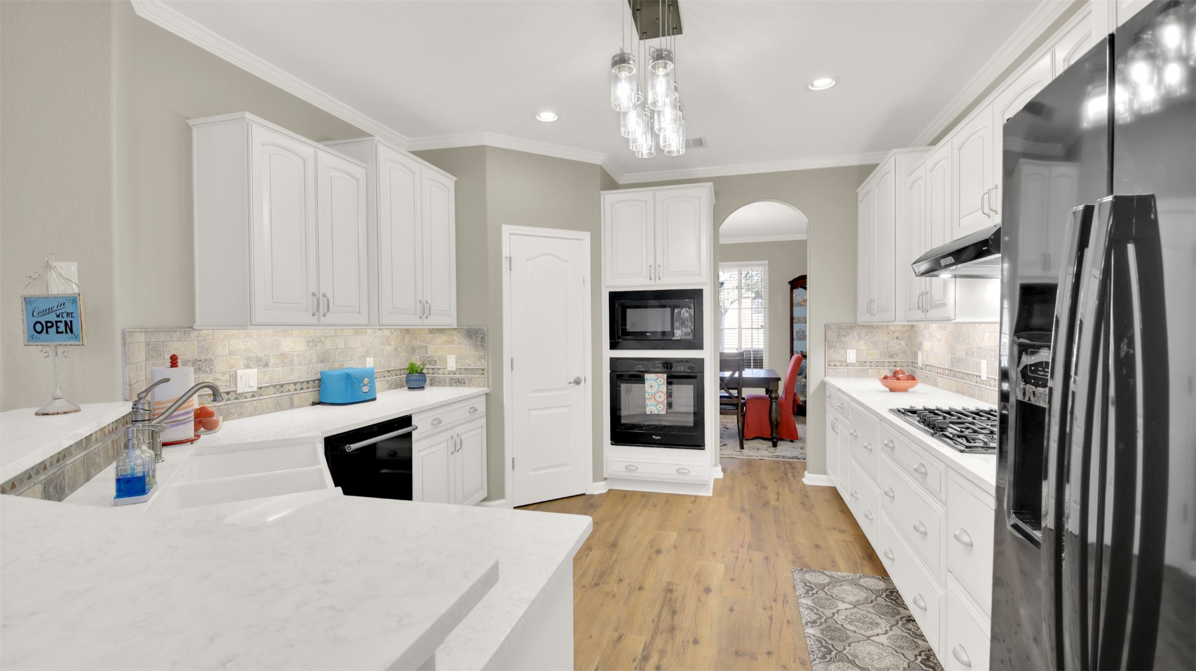 1210 Mathias Street Cedar Park, TX 78613 - Photo 10 of 31 Kitchen with black appliances, white cabinets, arched walkways, decorative light fixtures, and ornamental molding
