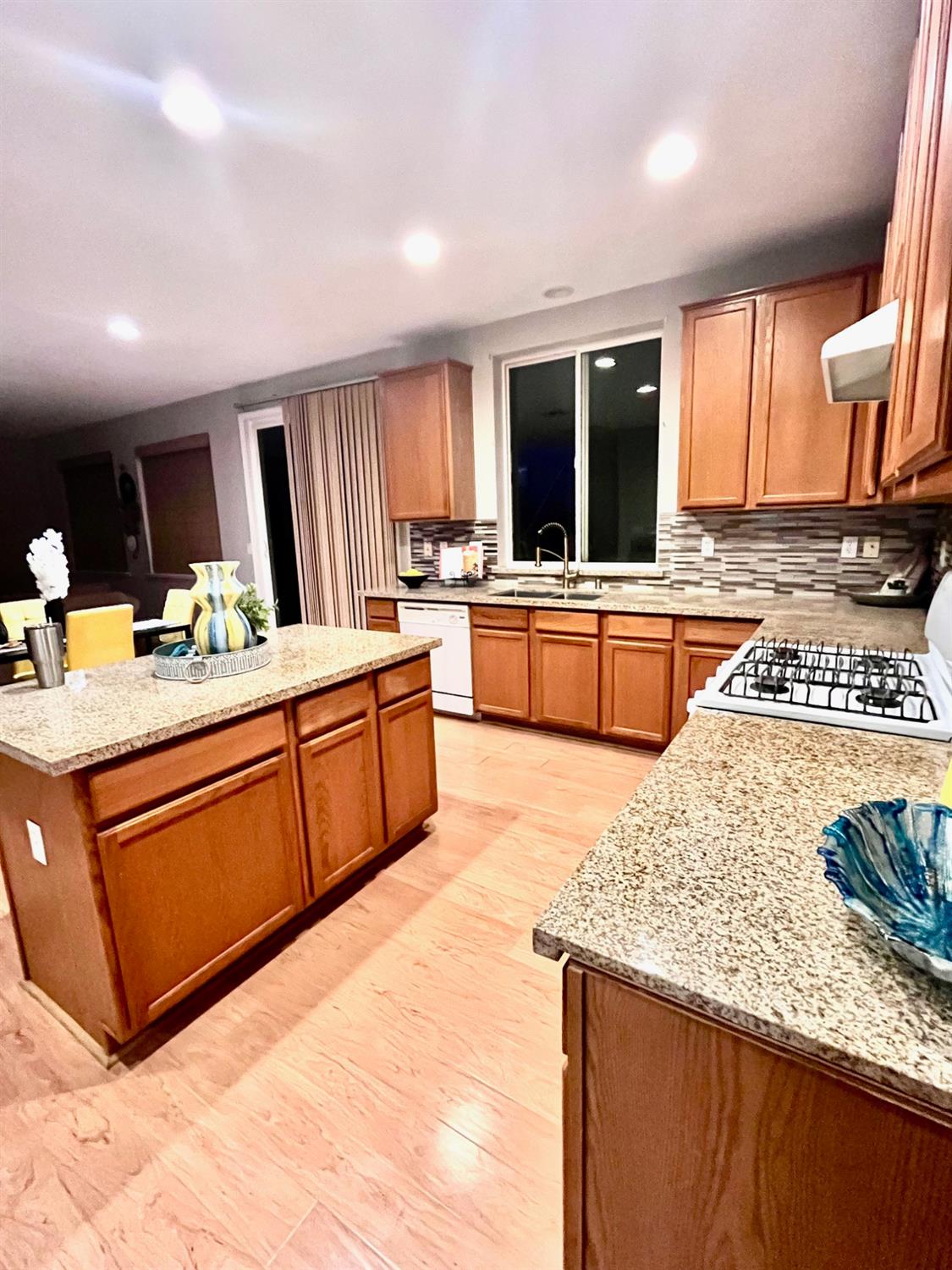 1450 Longhorn Lane Patterson, CA 95363 - Photo 25 of 32 a large kitchen with kitchen island granite countertop wooden cabinets a stove a sink and a large window