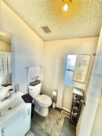 a bedroom with a bed a mirror on the dresser and a flat tv screen