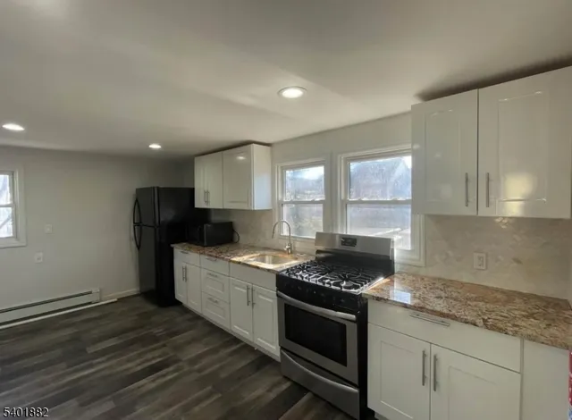 a kitchen with granite countertop stainless steel appliances a stove sink and cabinets