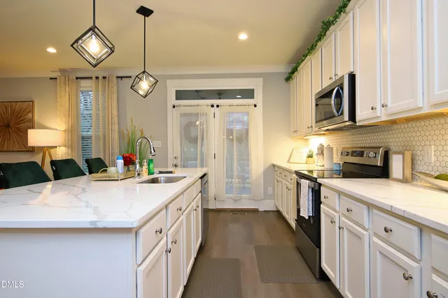 a kitchen with stainless steel appliances granite countertop a stove a sink a microwave a island with a dining table and chairs