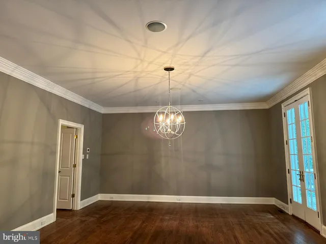 a view of an empty room with wooden floor and windows
