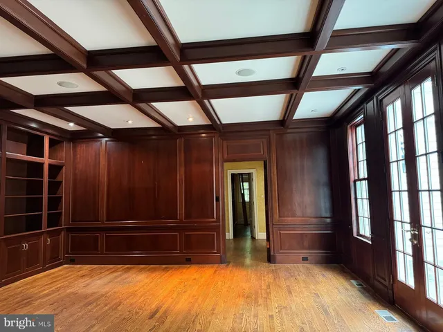 an empty room with wooden floor fireplace and windows