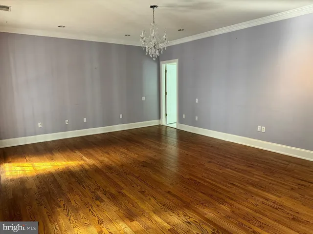 a view of a hallway with wooden floor and a living room