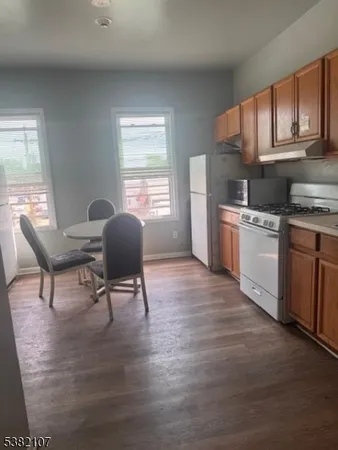 a living room with stainless steel appliances granite countertop furniture wooden floor and a window