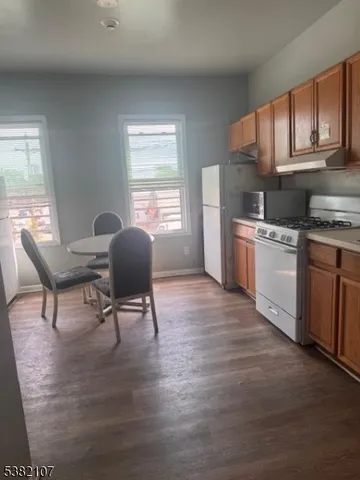 a living room with stainless steel appliances granite countertop furniture wooden floor and a window