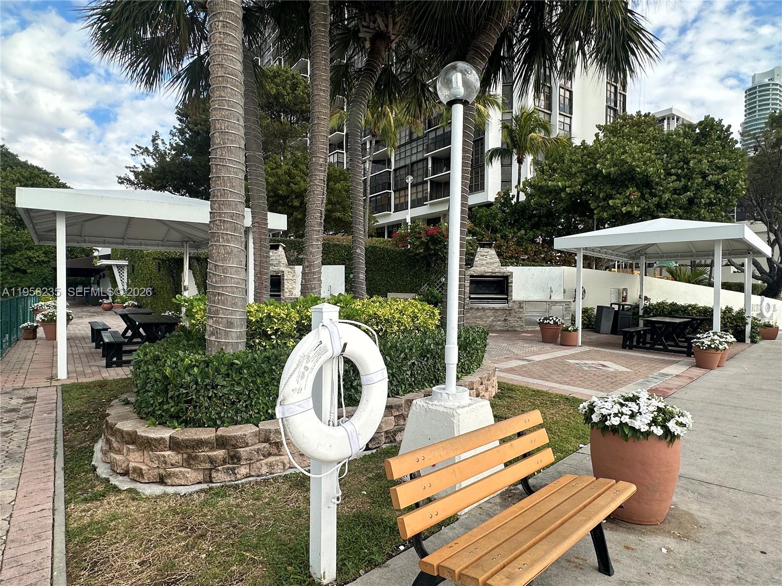 1925 Brickell Avenue, Unit D1201 Miami, FL 33129 - Photo 23 of 27 a patio table and chairs with potted plants and palm trees