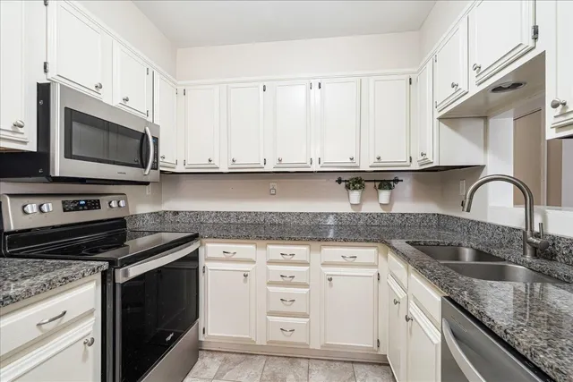 a kitchen with granite countertop white cabinets and stainless steel appliances