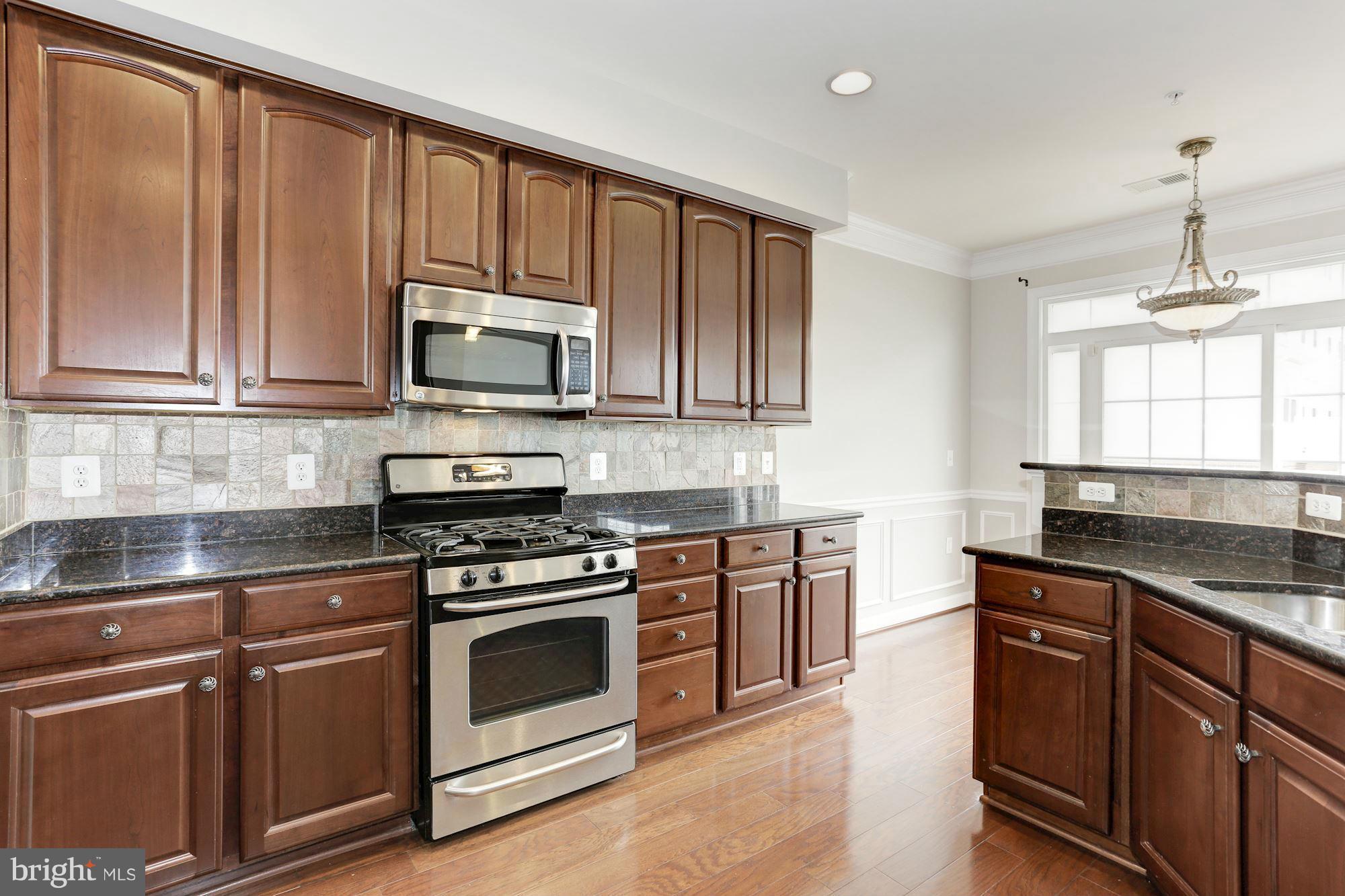 a kitchen with granite countertop wooden cabinets and a stove top oven