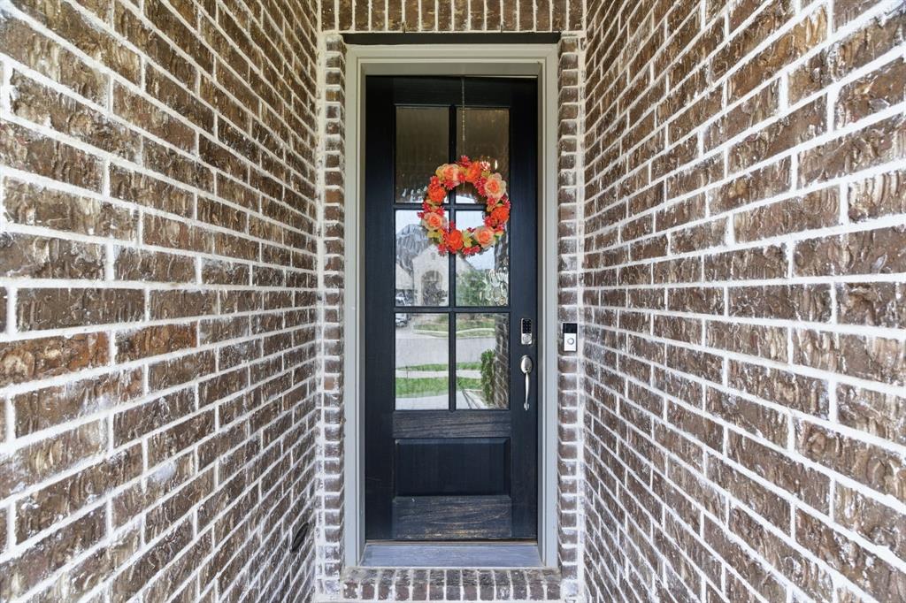 3721 Prickly Pear Road Little Elm, TX 75068 - Photo 3 of 21 Inviting dark-paneled door with glass inserts, framed by a robust brick exterior, featuring a smart doorbell system and a durable threshold