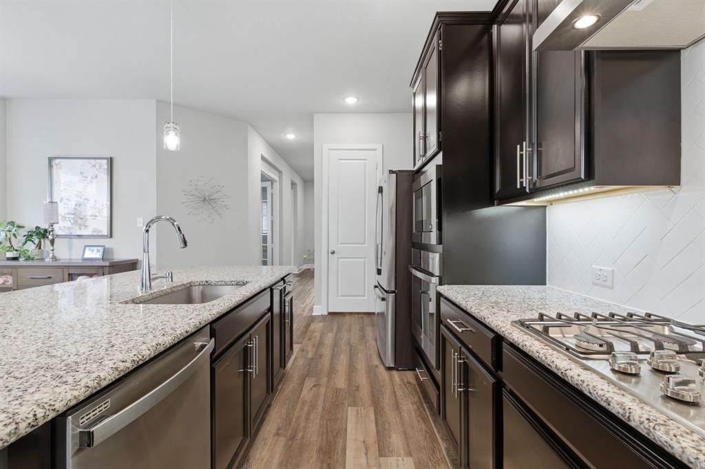 3721 Prickly Pear Road Little Elm, TX 75068 - Photo 9 of 21 Modern kitchen featuring wood-finish flooring, dark cabinetry, and light speckled countertops