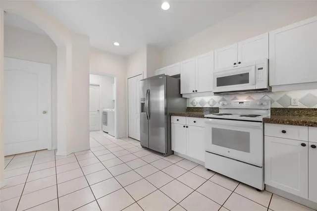 an empty room with windows and chandelier fan